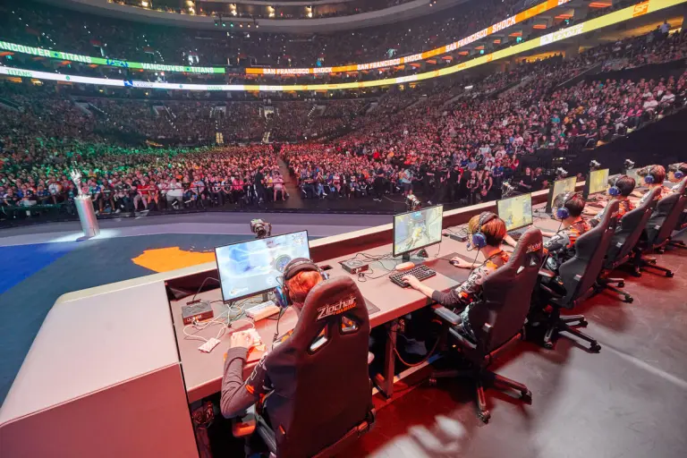 A big crowd watches Overwatch League players play on stage.