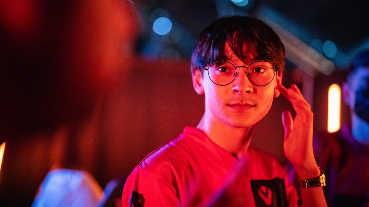 TenZ, wearing a Sentinels jersey and lit in bright red light, looks into the camera.