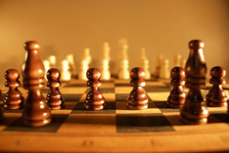 A chess board mid-game bathed in yellow light.