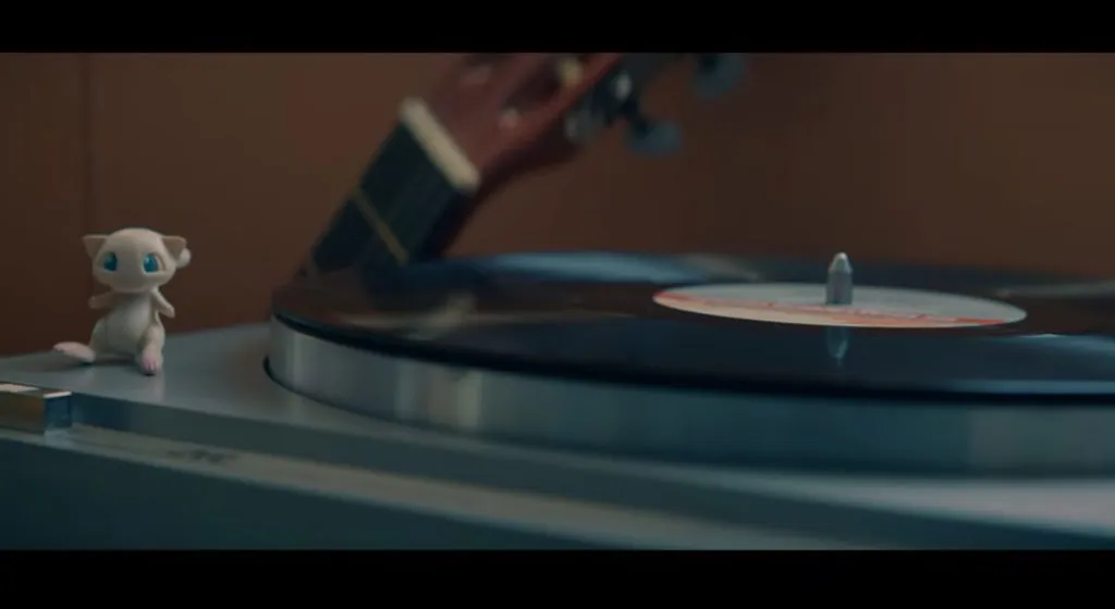 A Mew toy sits next to a record player.