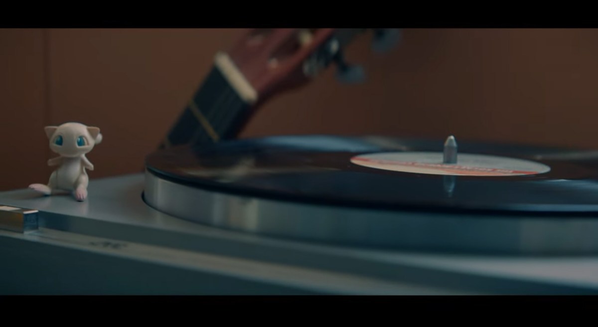 A Mew toy sits next to a record player.