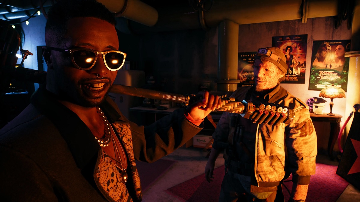 Two people in a dark room, one is wearing sunglasses.