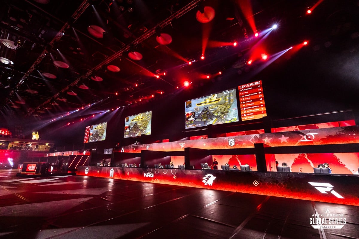 The ALGS Split 2 Playoffs stage, with several teams in their areas and esports logos on red screens in front of them.