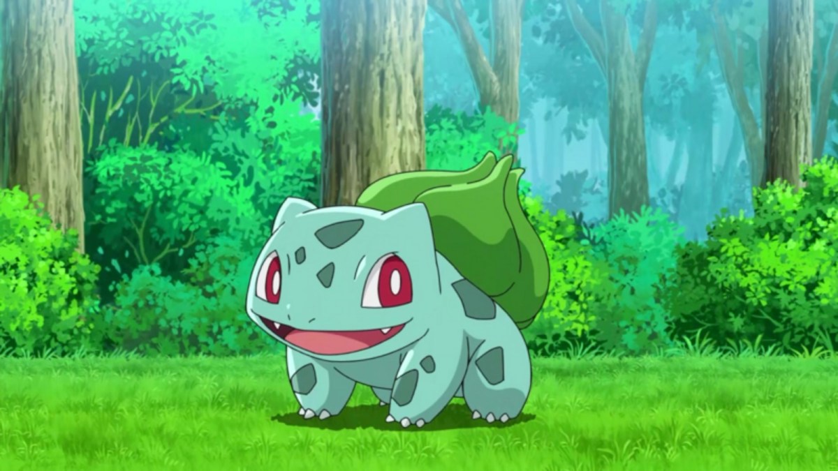 The Pokemon Bulbasaur shown in a wooded environment on a patch of grass and in front of several trees.