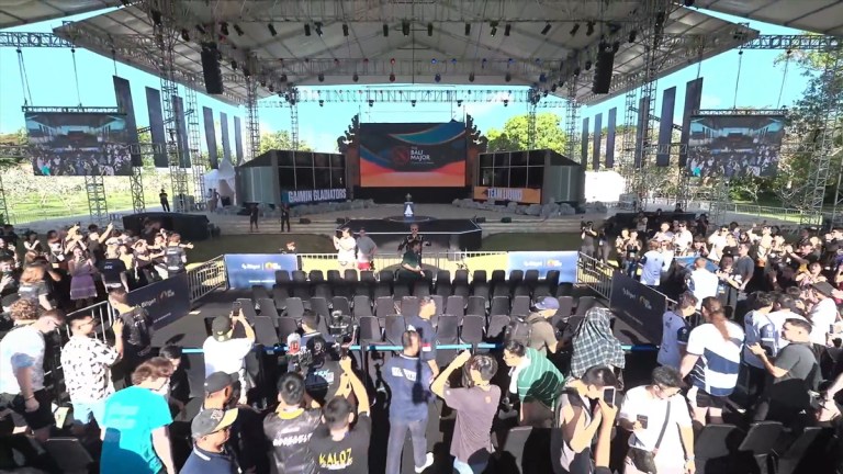 An outdoor stage featuring two team booths and a small crowd at the Bali Major.