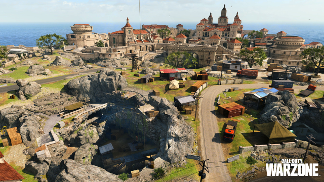 A grand castle and town sits in the distance, while an underground cove opens up with a smattering of buildings spread outside the town walls in Warzone.