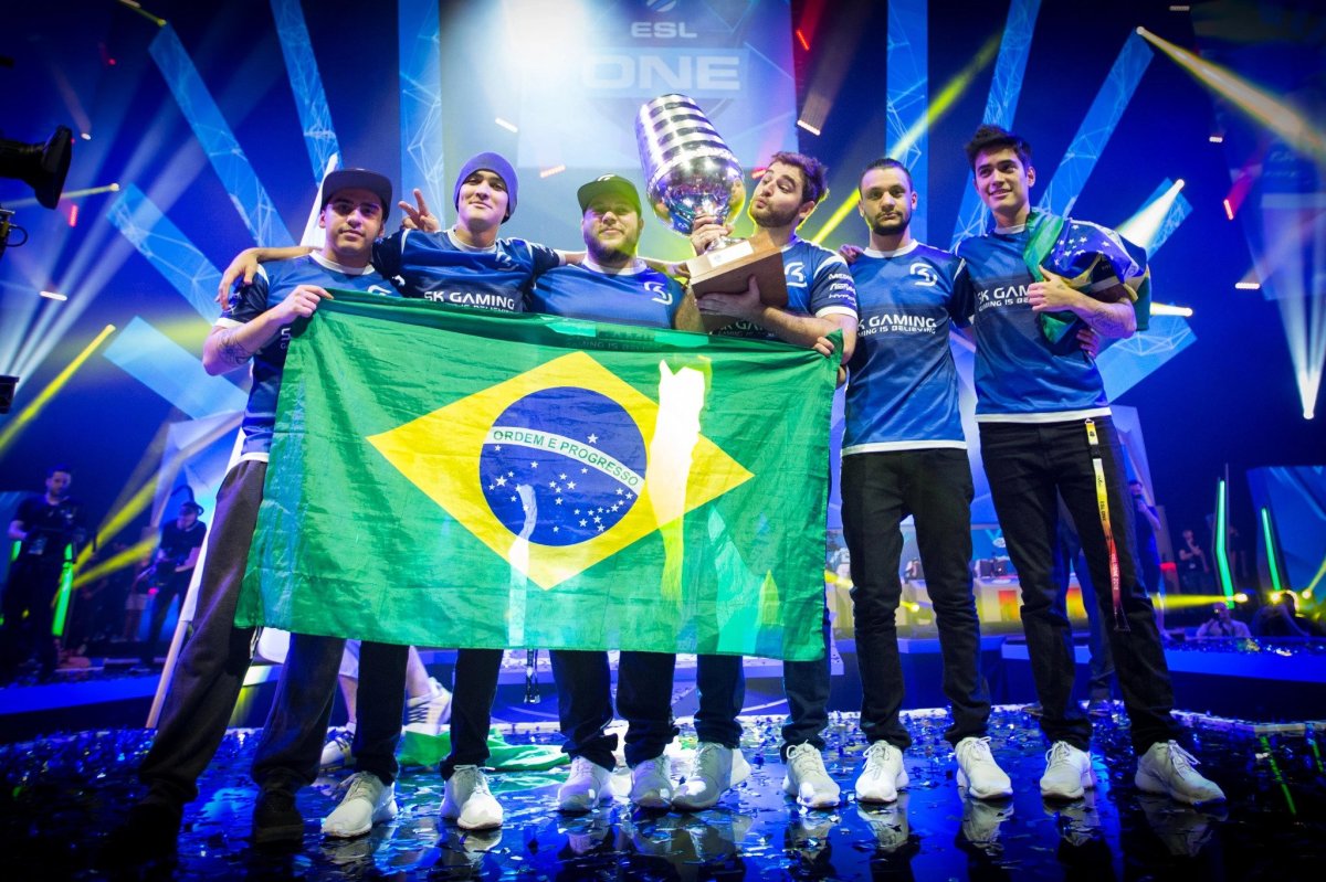 SK posing with the Brazilian flag on stage, FalleN is holding the ESL One Cologne 2016 trophy.