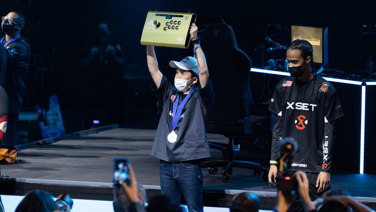 Kawano lifing his golden arcade stick after winning Evo 2022.