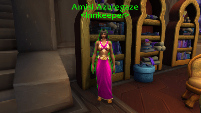 Legion Dalaran Innkeeper in a pink dress standing next to a book shelf.