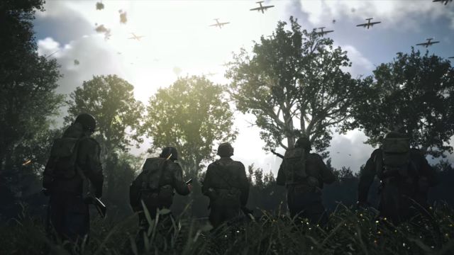 Image of soldiers on a field in a woodland clearing with warplanes overhead in Call of Duty World War II. The sky is in a blue coloration and a beam of light is streaking through.