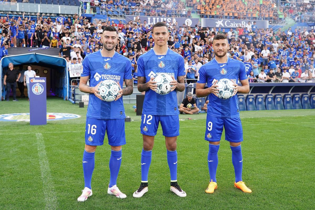 Getafe forward Mason Greenwood and two other signings holding a football in front of a crowd in the stands.