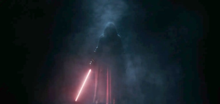 A shadowed figure in a cloak holding a red lightsaber in a promotional image for Star Wars: Knights of the Old Republic remake