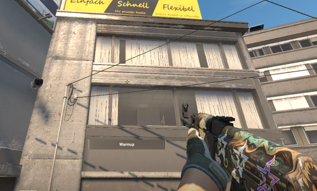 A CS2 character holding an AK-47 and pointing towards A Site.