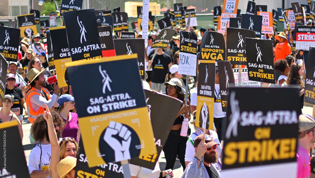 SAG-AFTRA members march on the street with strike banners and signs