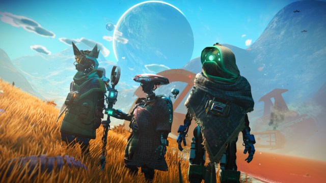 Image from No Man's Sky featuring three robotic alien creatures wearing hooded cloaks in a grassy field.