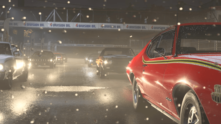 Cars on the track at the start of a race in Forza Motorsport, with headlights glaring and specs of rain on the camera.