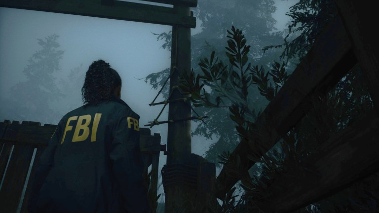 Saga looks at a hanging wooden cult symbol in the woods