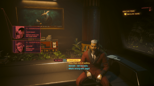 Mr Hand.s sitting on the couch in his penthouse while explaining Jago and Bennett to V (Cyberpunk 2077).