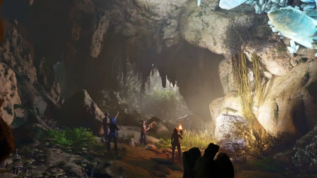 A bunch of characters in Ark: Survival Ascended entering a cave.