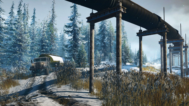 A truck in the grass with snowy trees in the background and a oil pipeline above