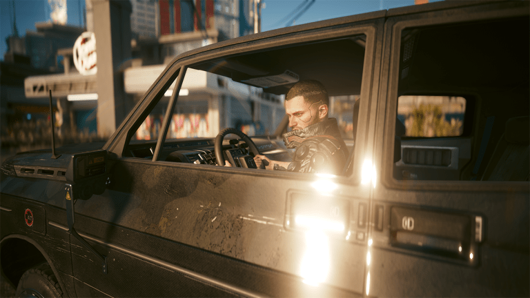 A man behind the wheel of a futuristic car in Cyberpunk 2077.