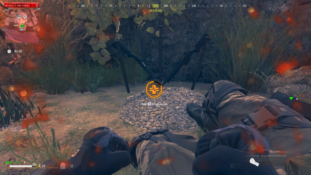 A player is downed and bleeding out in front of a gravestone marked by guns.