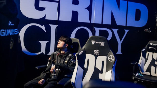 T1 Faker sits down on a chair, holding a water bottle.