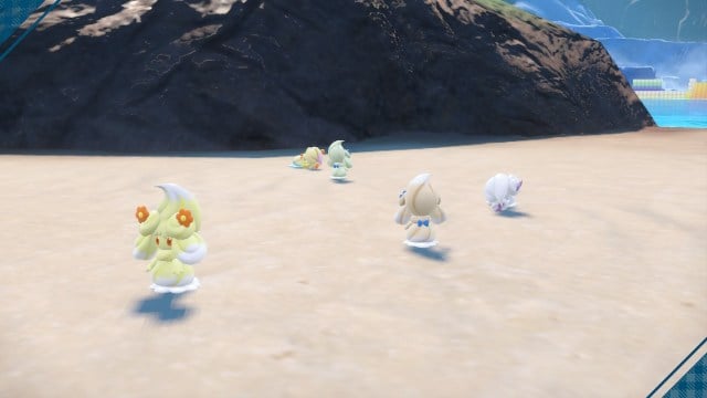 A group of Alcremie walk down a beach in Pokémon Scarlet and Violet.