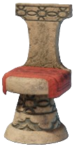 A stone chair with a round base and seat with a red cloth draped over the seat.