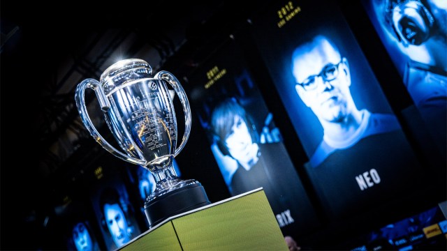 The IEM Katowice trophy on a plinth with banners of former champions displayed in the background.