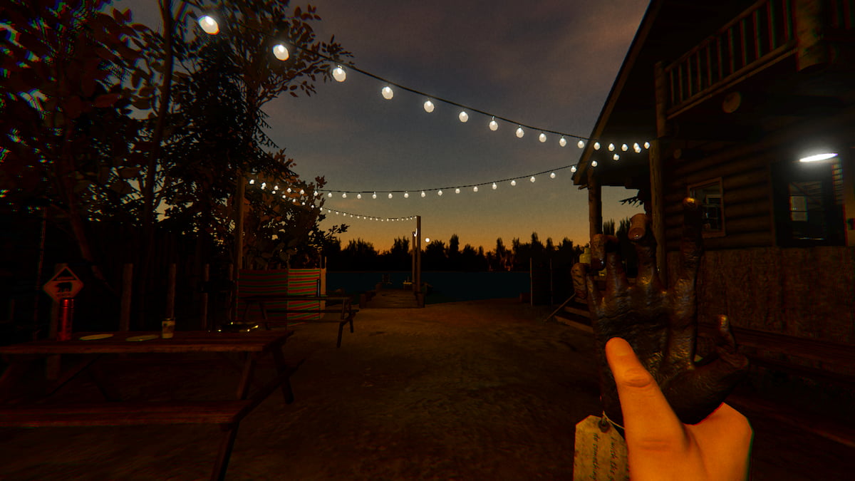 Holding a Monkey Paw while standing under some lit string lights at Male Lodge Campsite in Phasmophobia.