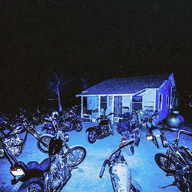 An image of the cover art to Bandit, a song in Fortnite Festival. This cover is blue and features various motorbikes in front of a small house. 