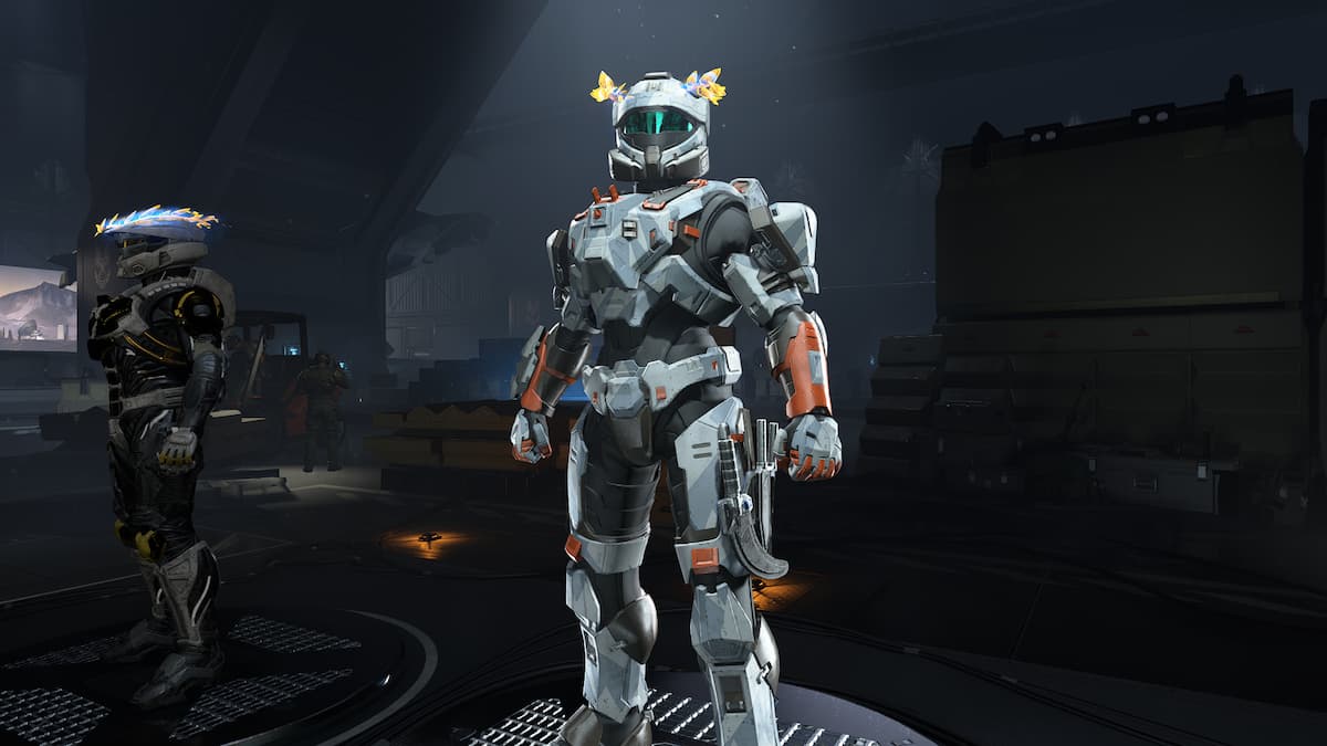 A Spartan standing in the armory hall with the Winterslash Flame armor coating equipped. The coating is light gray and rust orange, with a geometric camo pattern.