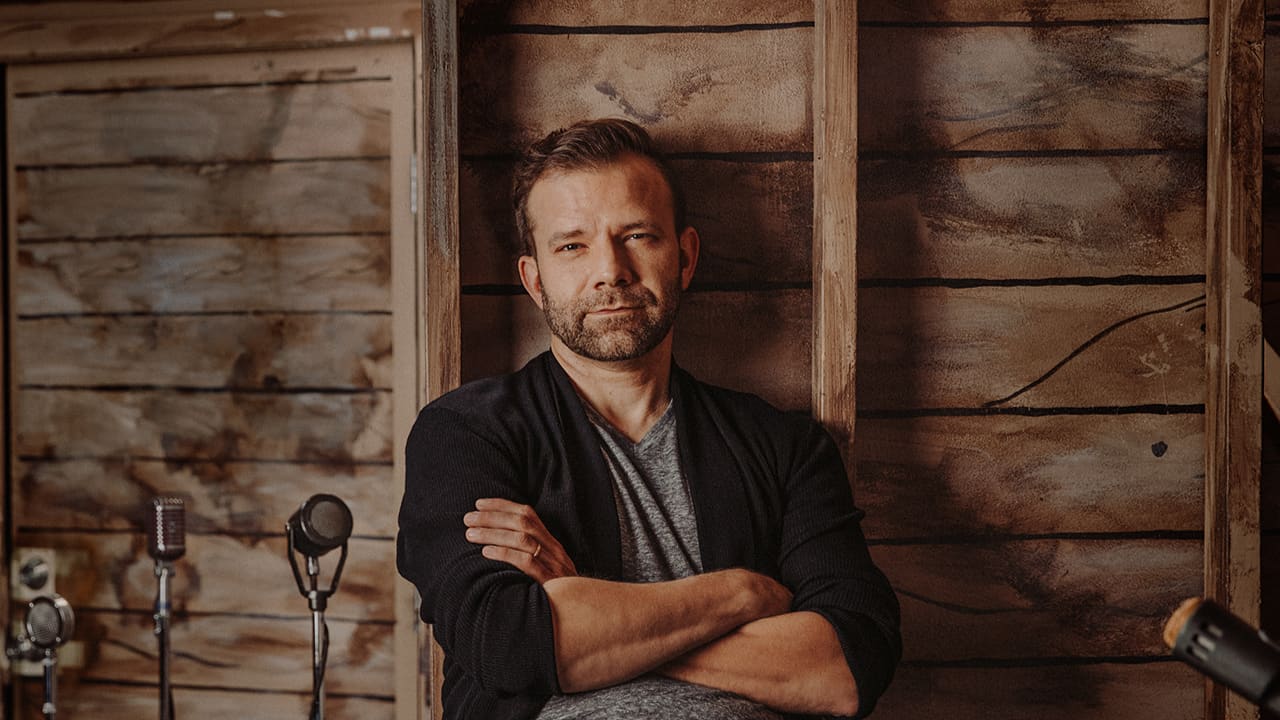 An editorial shot of Liam O'Brien with his arms crossed.
