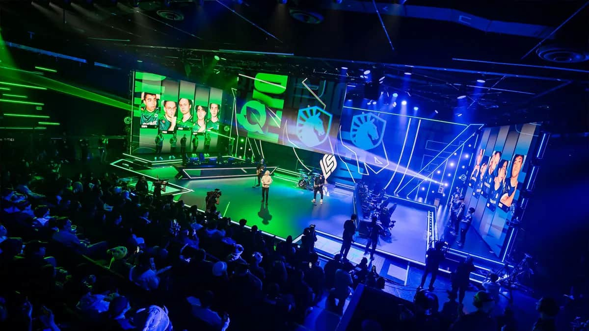 FlyQuest takes on Team Liquid in the LCS, both logos on stage with green and blue lights flashing.