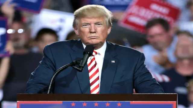 Donald Trump standing at a podium, about to speak into a microphone.