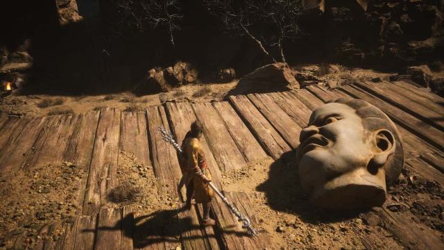 The Destined One stands atop a ledge, with two Buddha heads: one to his right and another one on the floor across from him.