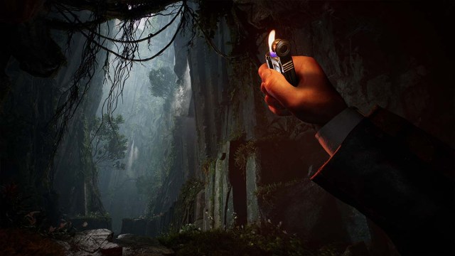 A character raising a lighter from a first-person perspective to illuminate a dark cave