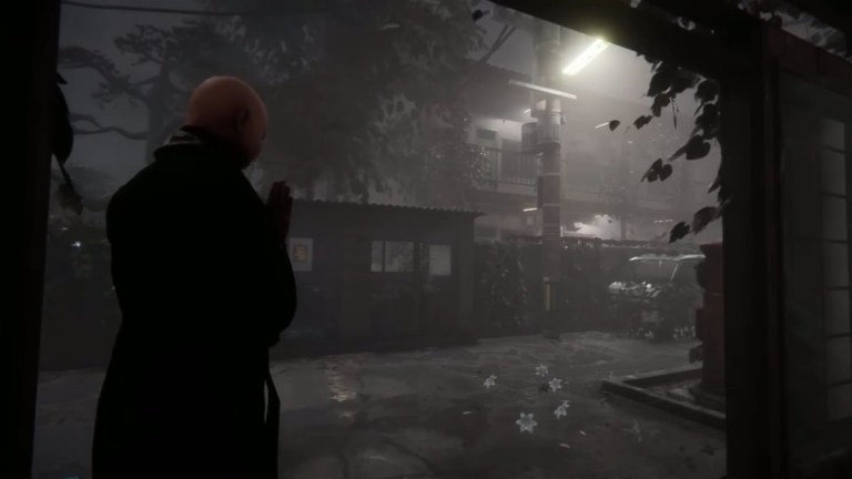 Establishing shot of the village, outside the bathhouse, with the Priest (back to us) praying on the left side of the screen