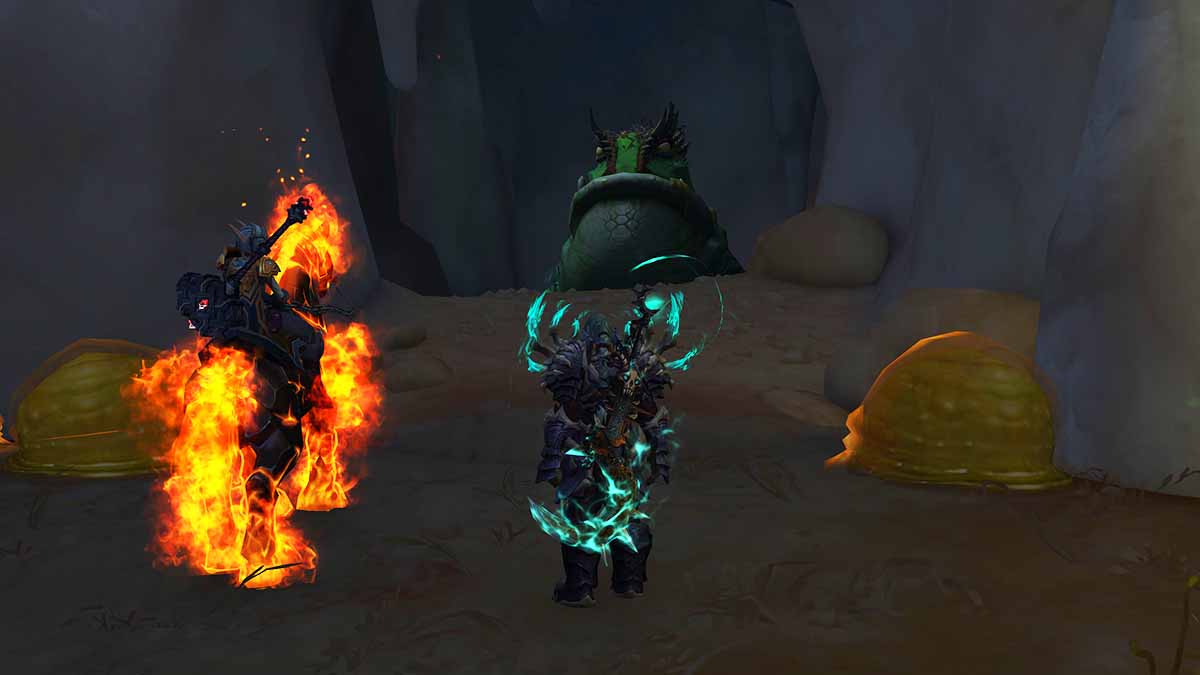 A WoW Death Knight and a character on a fiery horse standing in front of a cave with a giant frog inside