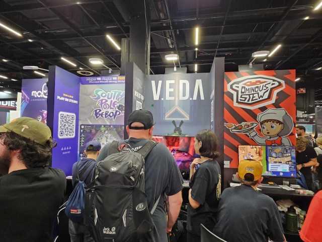 A crowd stands around gaming booths.