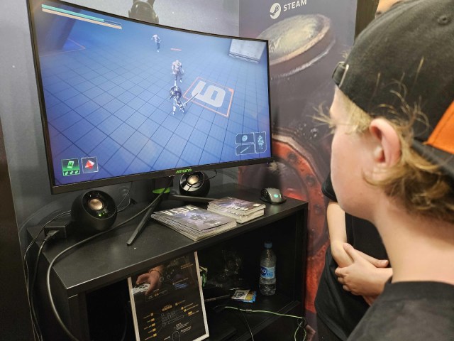 A man in a hat plays a video game on a tv screen.