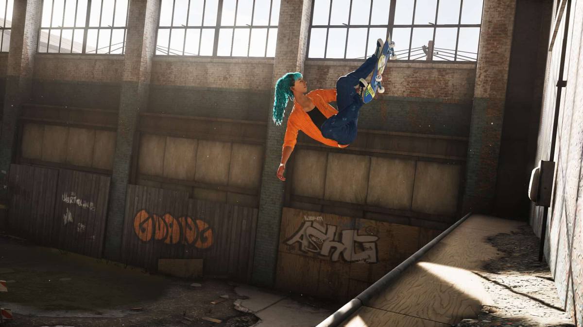 A blue-haired skater with a bright orange sweater flies up a ramp.