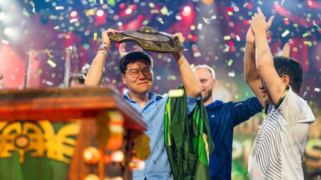 Blitz, coach for Team Liquid, lifts Dota 2's Aegis of Champions as confetti falls around him at TI 2024.