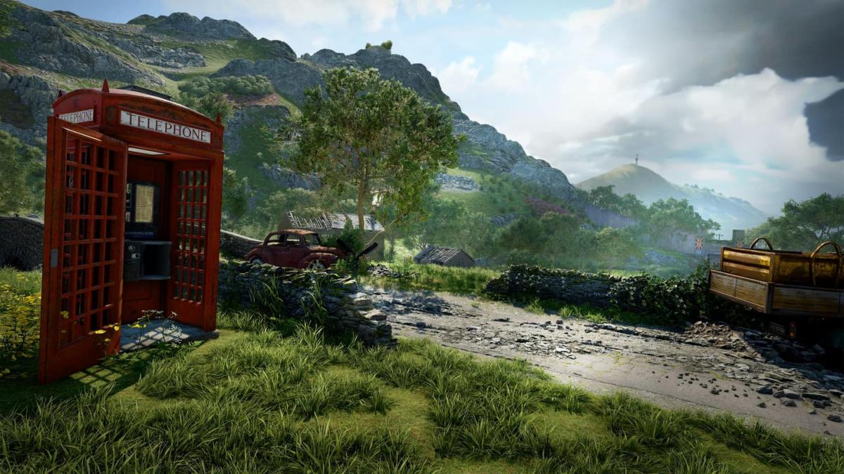 A red phone booth sits on a country lane that's fallen into disrepair.